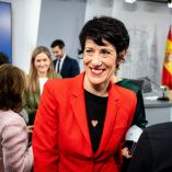 Elma Saiz, ministra de Inclusión, Seguridad Social y Migraciones y portavoz del Gobierno, sonríe durante la rueda de prensa tras el Consejo de Ministros en Madrid, con periodistas y miembros del Ejecutivo al fondo.