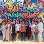 Grupo de mujeres mayores integrantes de Abuelas BUM BUM posan sonrientes frente a un mural colorido con grafiti que lleva el nombre del proyecto en Morelia, como parte de su iniciativa de rap y vejez activa.