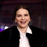 Juliette Binoche sonríe en la alfombra roja del estreno de “Queen at Sea” en la 76ª Berlinale, en Berlín, con abrigo oscuro y camisa blanca, durante la presentación oficial de la película en competencia.