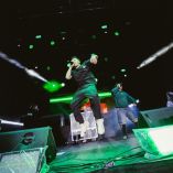 DVM, nombre artístico de Diego Villacís, canta y salta en el escenario durante un concierto de música urbana acompañado por otro intérprete y un DJ.