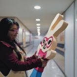 Xóchitl, voluntaria del IMSS, sostiene un muñeco de conejo frente a la puerta de la ludoteca del área oncológica en el Hospital de Pediatría del CMN Siglo XXI.