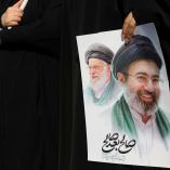 Una mujer sostiene una foto con Ali y Mojtaba jamenei.