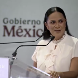 Ariadna Montiel habla en podio transparente con logotipo del Gobierno de México y micrófonos durante acto público sobre programas sociales en Quintana Roo.