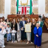 Víctor González Herrera posa con la Medalla al Mérito Turístico y un reconocimiento en el pleno del Congreso de la CDMX junto a legisladoras, asistentes y la botarga del Dr. Simi.