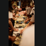 Personal de cocina trabaja en línea de preparación con utensilios y platos, siguiendo procesos de seguridad alimentaria en restaurante con sistema HACCP.