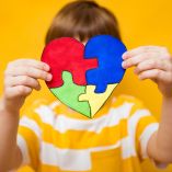 Kid boy hands holding puzzle heart, child mental health concept, world autism awareness day, teen autism spectrum disorder awareness concept