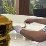 Empleado manipula la llave de cierre hermético de un ataúd dorado de acero calibre 18 exhibido en una funeraria de Colima