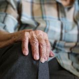 Un adulto mayor sentado con una mano sobre su rodilla