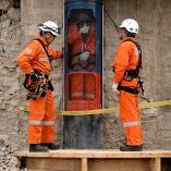 Cápsula Fénix con un minero en su interior durante el rescate en la mina San José en Chile en 2010, vigilado por rescatistas.