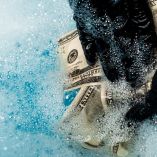 close up of man in rubber gloves washing dollar banknotes in soap bubbles with water