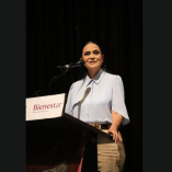 Ariadna Montiel Reyes habla en un podio con logotipo de Bienestar durante un evento oficial, frente a micrófono en escenario interior