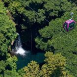 Cabina del teleférico de Uruapan cruza sobre vegetación densa y una cascada en la Barranca del Cupatitzio en Michoacán