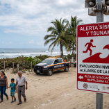 Cartel de alerta sísmica y evacuación por tsunami en una playa de Chiapas tras el sismo de magnitud 7.4.