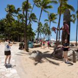 Personas se toman fotografías frente a la estatua de Duke Kahanamoku en la playa de Waikiki