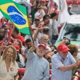 Brazil's President and presidential candidate Luiz Inacio Lula da Silva (C) waves a national flag next to former federal deputy Aurea Carolina (L) and federal deputy Patrus Ananias (R) during a campaign rally in Belo Horizonte, Minas Gerais state, Brazil on October 2, 2026. Brazilians go to the polls on October 4, 2026, in a tight race led by leftist President Luiz Inacio Lula da Silva and right-wing senator Flavio Bolsonaro, son of former president Jair Bolsonaro. (Photo by Gledston TAVARES / AFP)