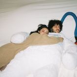Selena Gomez abraza a Benny Blanco mientras ambos descansan juntos sobre una cama.