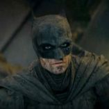 Robert Pattinson caracterizado como Batman, con máscara negra, traje oscuro y el rostro cubierto de suciedad en The Batman.