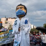 Marcha de trabajadores del IMSS y agremiados del SNTSS exigiendo un salario digno, acompañados de una figura gigante de un trabajador de la salud con cubrebocas.