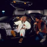 Doc Brown sentado en el DeLorean conversa con Marty McFly durante una escena nocturna de Volver al futuro.