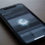 Celular negro sobre una mesa con un símbolo de carga en la pantalla que representa un teléfono trabado.
