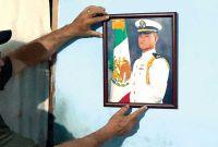 El padre de Luis Enrique Castillo Terrones acomoda uno de sus retratos en la pared.