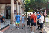 Grupo de turistas camina por una calle del Centro Histórico de Mazatlán, frente a un edificio con columnas y locales comerciales, durante su visita al puerto tras el arribo de un crucero en el Carnaval 2026.