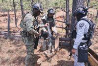 Elementos de la Secretaría de Marina inspeccionan un arma larga asegurada en zona boscosa de Del Nayar durante operativo contra enervantes.