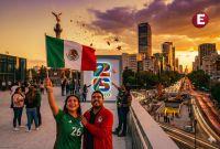 Pareja de aficionados celebrando con la bandera de México frente al Ángel de la Independencia y un letrero del Mundial 2026 al atardecer en la Ciudad de México.