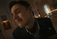Hombre con traje aparece en una habitación iluminada por velas durante una escena de American Horror Story 13.