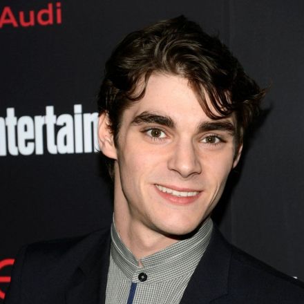 RJ Mitte, exnovio de Saint Sasha y actor de Breaking Bad, sonríe con traje negro frente a un fondo de Entertainment Weekly y Audi.