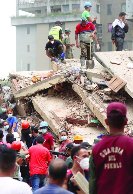 Personas buscan víctimas entre los escombros de un edificio derrumbado.