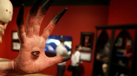 Escultura de una mano monstruosa con un ojo en la palma y dedos alargados, exhibida en una muestra de Guillermo del Toro.