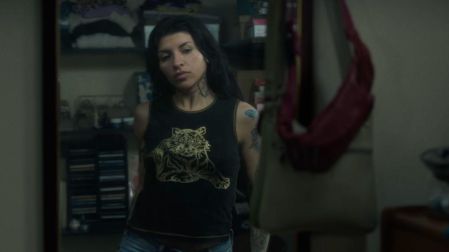 Cazzu con cabello negro, camiseta sin mangas con estampado de tigre y jeans azules en una escena del video Con otra.