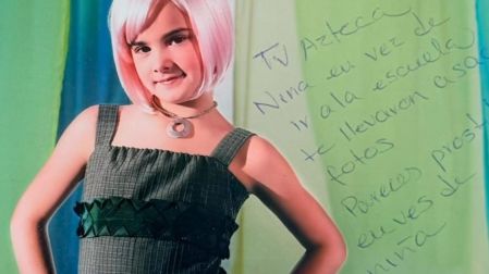 Gala Montes de niña con peluca rosa, vestido verde y collar, junto a una dedicatoria manuscrita sobre la fotografía.