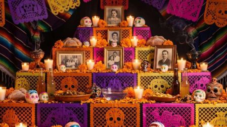 Ofrenda de Día de Muertos de varios niveles con fotografías, flores de cempasúchil, veladoras, calaveritas y pan de muerto.