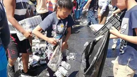 Mucha gente entre ellos, niños, robando cervezas después de que volcó un camión 