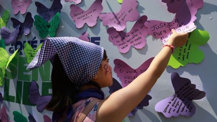 Una pequeña pega un mensaje en el que exige justicia para las mujeres