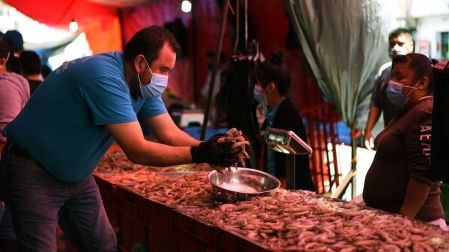 Una persona pone puños de camarón en una bandeja para venderlos.