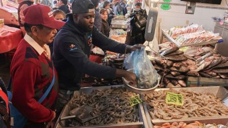 Dos personas, comerciantes, pesando camarón en un mercado de México.