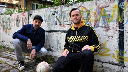 Members of Bosnian Hip-Hop band "Dubioza Kolektiv", Brano Jakubovic (L) and Vedran Mujagic pose with a ball in Sarajevo on June 2, 2026. With brass, guitars, and a music video overflowing with grilled meat, Bosnia has delivered the first World Cup anthem of 2026: "I Am from Bosnia, Take Me to America." the song had already accumulated several million views on different platforms. The song is a cover version of an earlier hit by the Bosnian rock band Dubioza Kolektiv and is rapidly becoming one of the signature songs (anthems) of the 2026 World Cup, which begins on June 11. (Photo by ELVIS BARUKCIC / AFP)