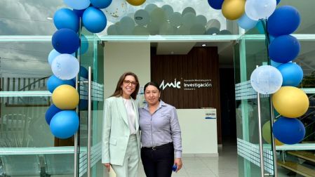 Dos asistentes posan frente al acceso del Centro de Investigación Clínica de AMIC en Pachuca, decorado para su inauguración oficial.