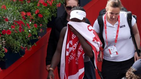 Victoria Mboko se cubre el rostro con una toalla después de tener que abandonar su partido ante la checa Karolina Pliskova.
