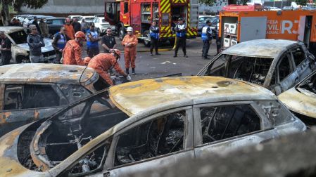 Bomberos y policías trabajan junto a vehículos calcinados en el lugar del accidente de un helicóptero en el barrio Recreio