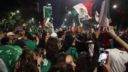 Miles de aficionados celebrando un triunfo de México ondeando banderas de noche en el Paseo de la Reforma.