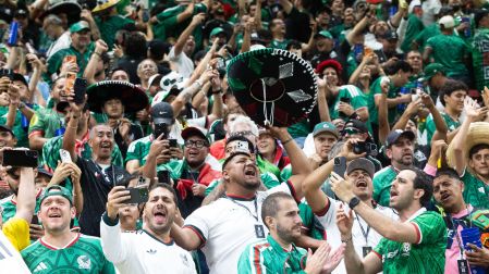 Multitud de aficionados mexicanos gritando y tomando fotos con sus celulares en las gradas de un estadio del Mundial.