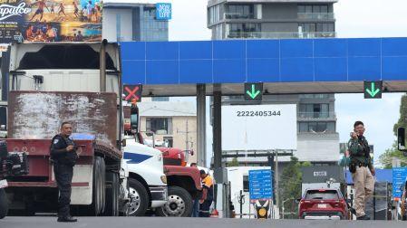 Tráileres bloqueando una caseta de peaje en Puebla mientras elementos de la policía vigilan la zona durante el paro nacional.