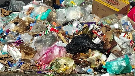 Pila de basura sin embolsar, plásticos y cartón abandonada en la vía pública, generando contaminación visual.