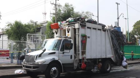 Camión recolector de basura de la alcaldía Cuauhtémoc estacionado y saturado de bolsas de residuos sólidos.