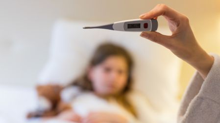 Mother checking body temprature on thremoeter in bedroom
