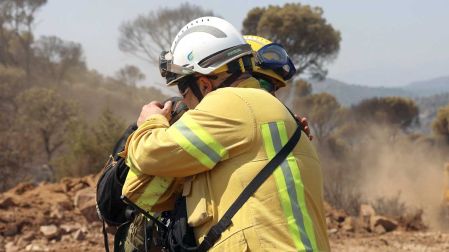 Dos bomberos españoles se abrazan.